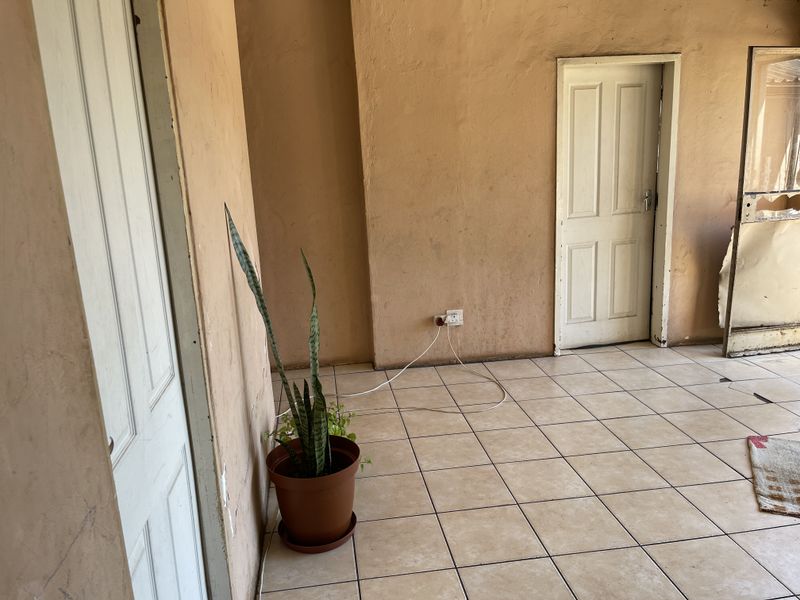 A vacant hallway area featuring tiled flooring and multiple access doors, requiring cosmetic updates to improve the overall finish and condition.