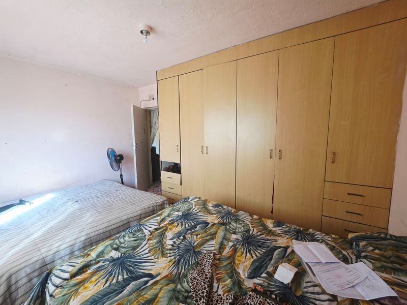 A bedroom featuring extensive built-in wooden cupboards with integrated drawers, providing ample storage space.