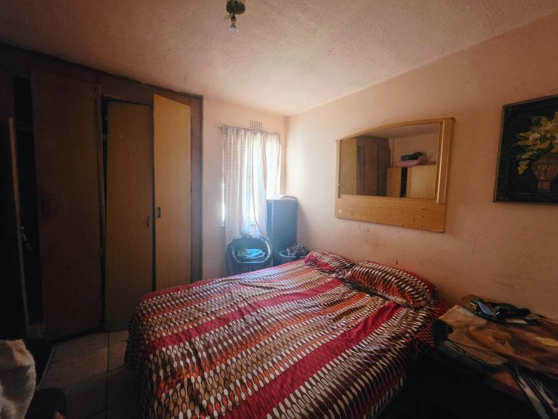 A bedroom featuring built-in cupboards and tiled flooring, requiring cosmetic updates to improve the overall aesthetic and condition of the space.