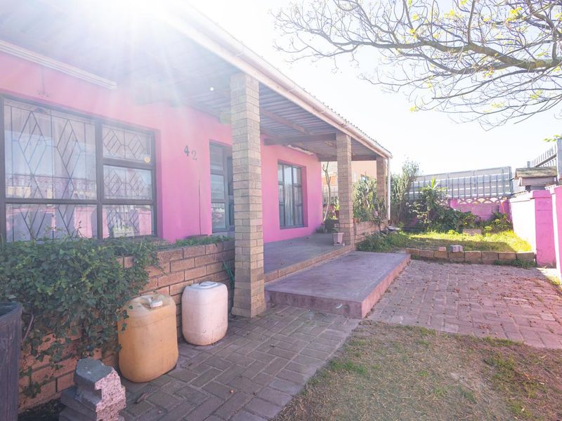 Rear exterior view of the property featuring a covered veranda, brick patio, and a garden area with boundary walling.