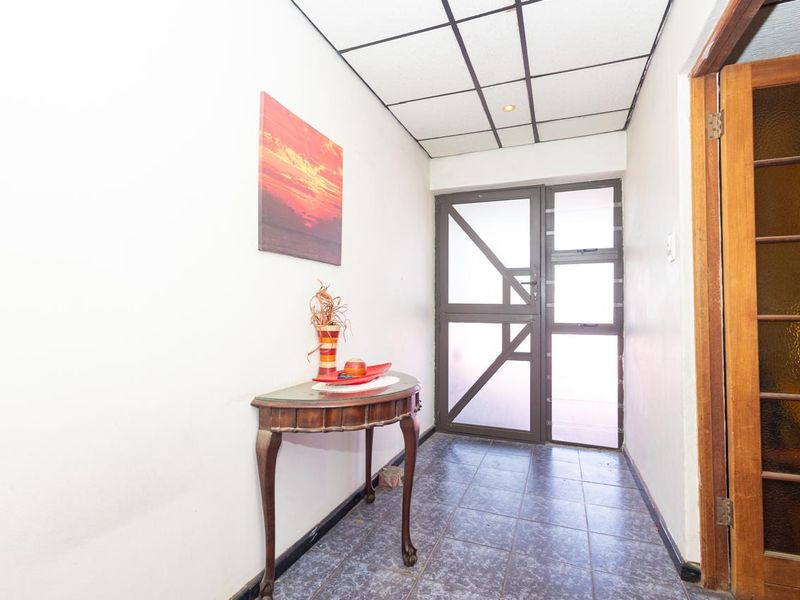 Entrance foyer featuring tiled flooring, a drop ceiling, and access to both an external aluminium door and an internal timber door.
