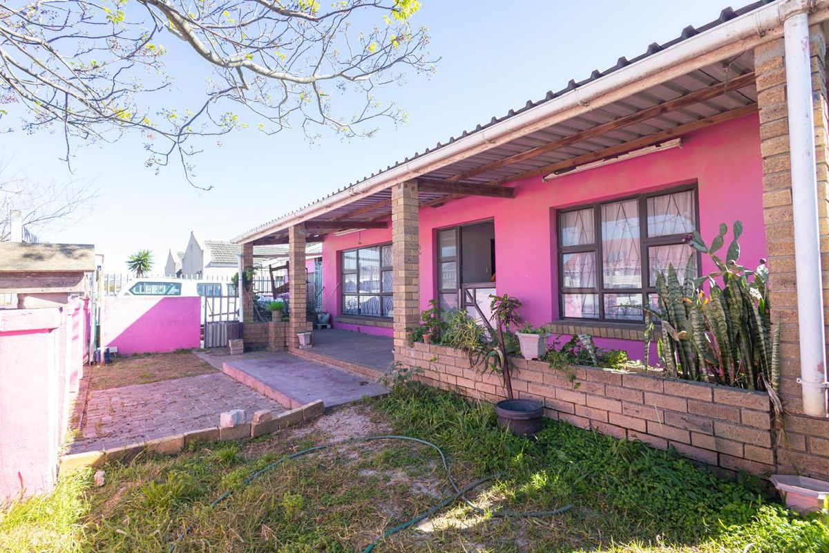 Rear exterior view of the house featuring a covered patio, brick planter boxes, and a paved area leading to the garden.
