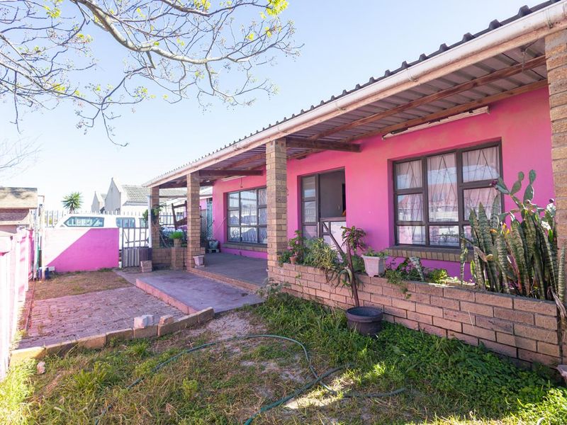 Rear exterior view of the house featuring a covered patio, brick planter boxes, and a paved area leading to the garden.