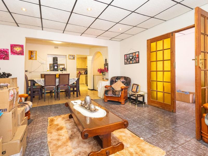 Open plan living and dining area featuring tiled flooring, a suspended ceiling with recessed lighting, and an arched transition to the kitchen space.