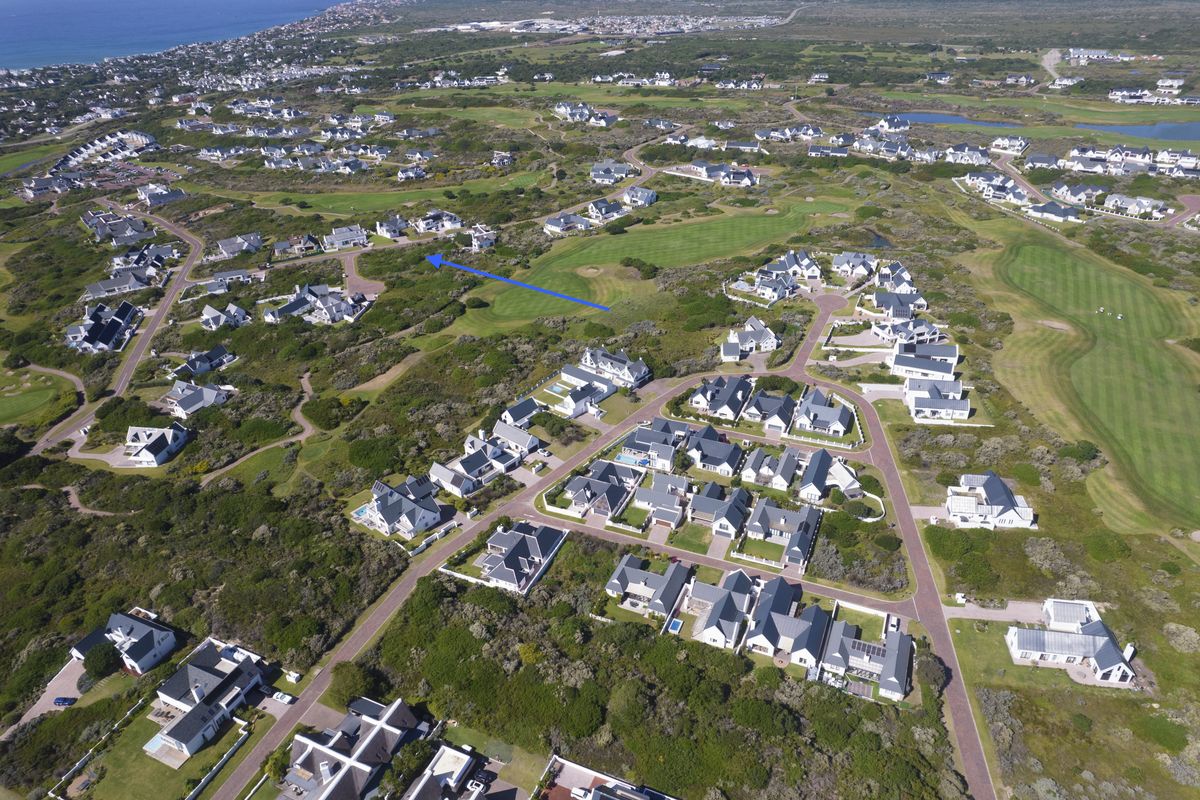 Aerial view of a residential estate featuring a golf course and surrounding coastal landscape, highlighting the location of the vacant land plot.