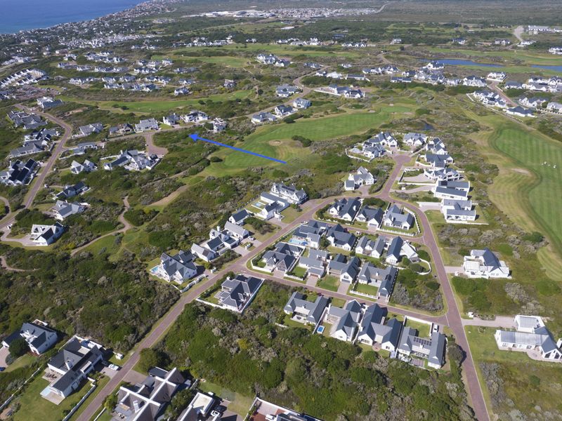 Aerial view of a residential estate featuring a golf course and surrounding coastal landscape, highlighting the location of the vacant land plot.