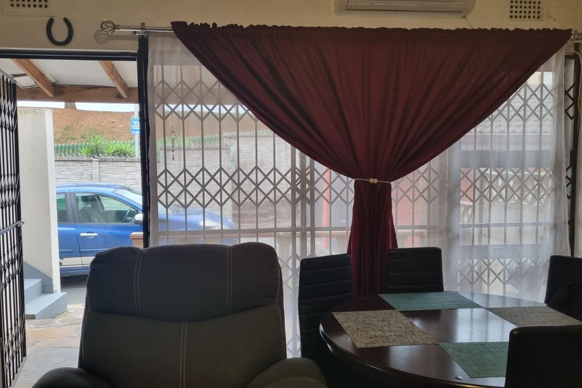 A living area featuring a sliding door with a security gate, providing access to the exterior, and an installed air conditioning unit.