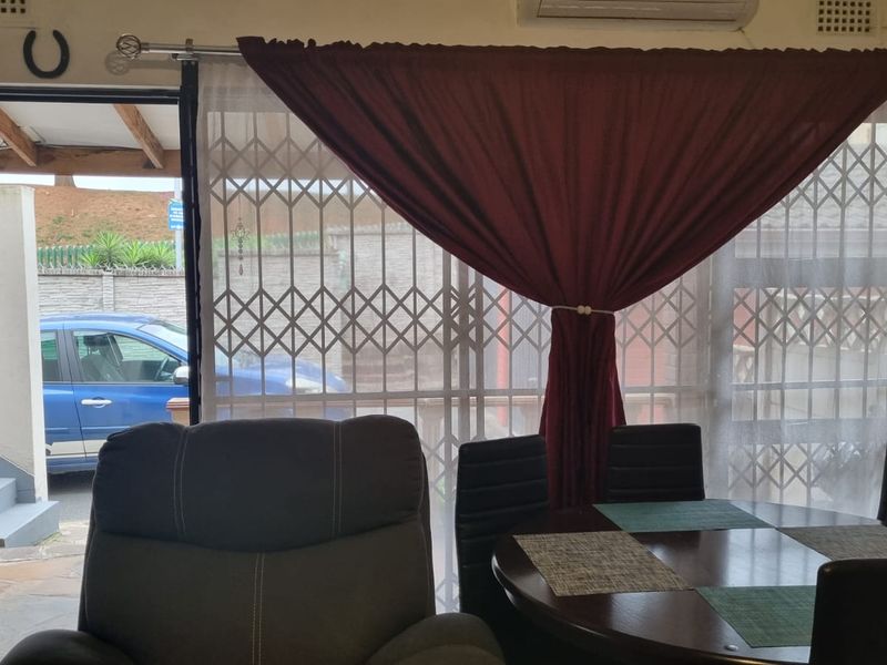 A living area featuring a sliding door with a security gate, providing access to the exterior, and an installed air conditioning unit.