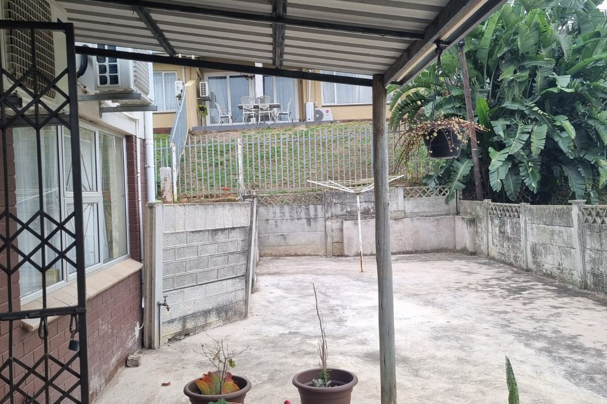 A private rear courtyard featuring a covered patio area, concrete paving, and secure boundary walling, offering potential for outdoor living enhancement.