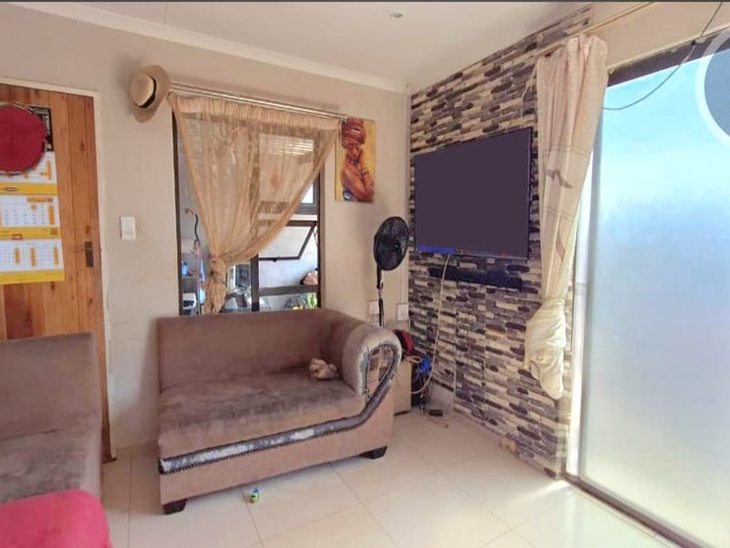 Living room featuring a stone-cladding accent wall, tiled flooring, and a sliding glass door providing natural light and access to the exterior.
