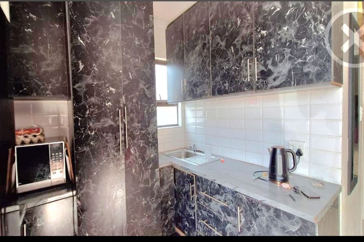 Compact kitchen featuring dark marble-effect cabinetry, white tiled backsplash, and integrated storage solutions.