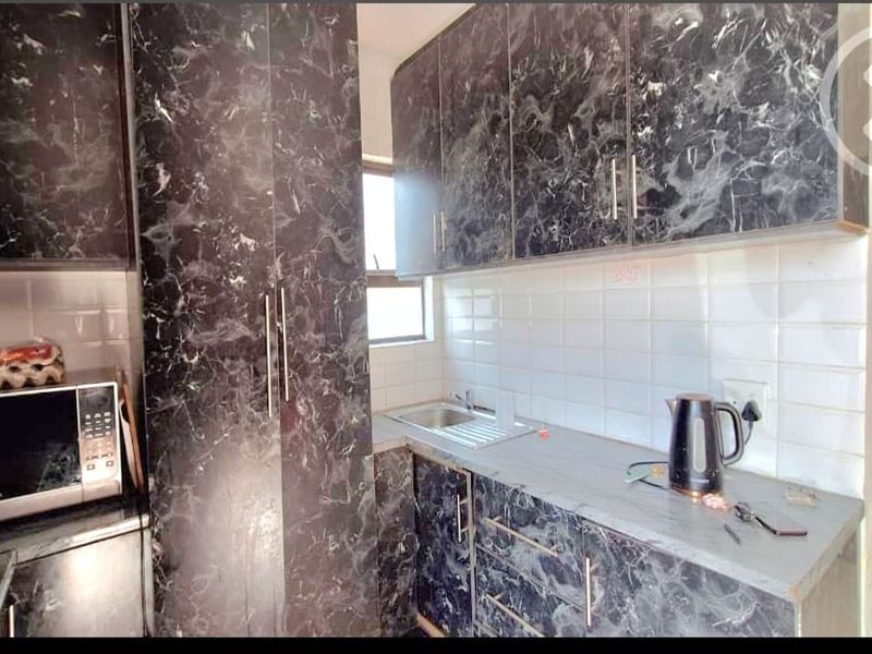 Compact kitchen featuring dark marble-effect cabinetry, white tiled backsplash, and integrated storage solutions.
