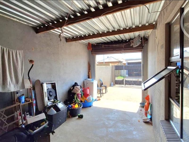 A functional garage space featuring a corrugated metal roof, concrete flooring, and a roller shutter door, providing secure parking or utility storage.