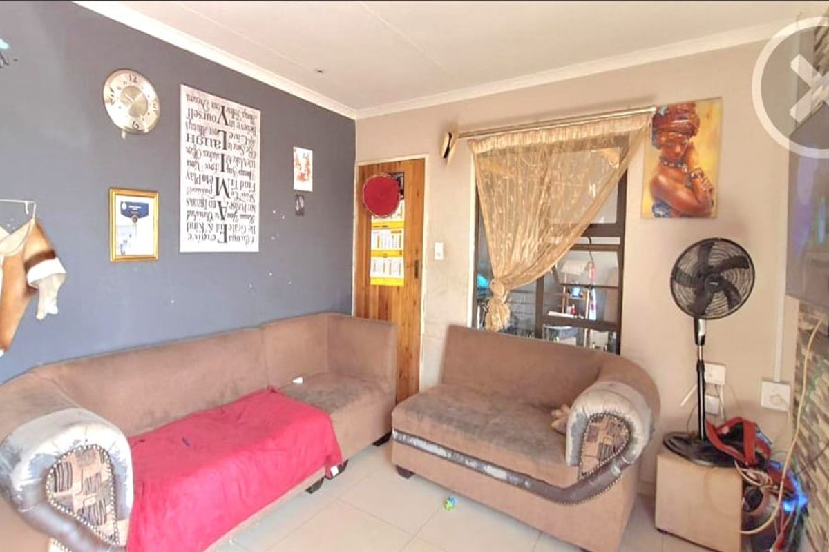 A living room area featuring tiled flooring and a timber door, providing a functional space with potential for cosmetic updates.