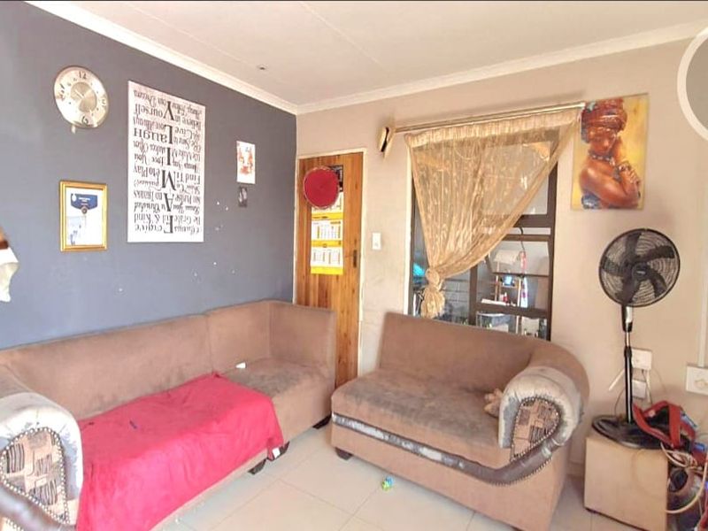 A living room area featuring tiled flooring and a timber door, providing a functional space with potential for cosmetic updates.