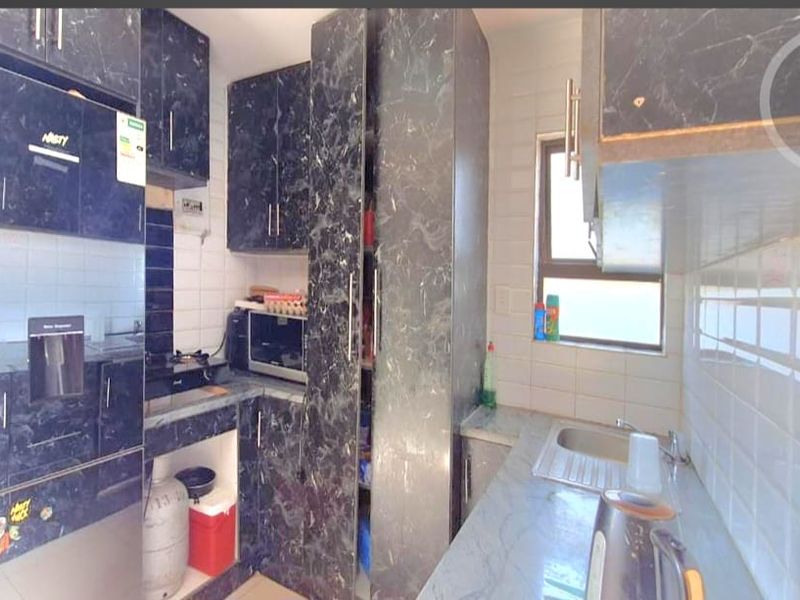 A compact kitchen featuring dark marble-effect cabinetry, tiled backsplash, and integrated storage solutions with a functional layout.