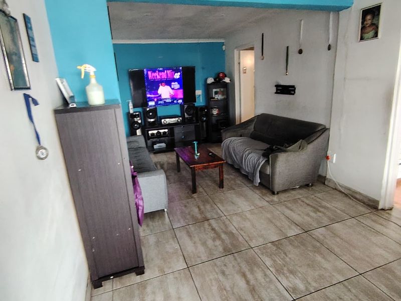 A living room featuring tiled flooring and recessed ceiling lighting, currently used as a lounge area.