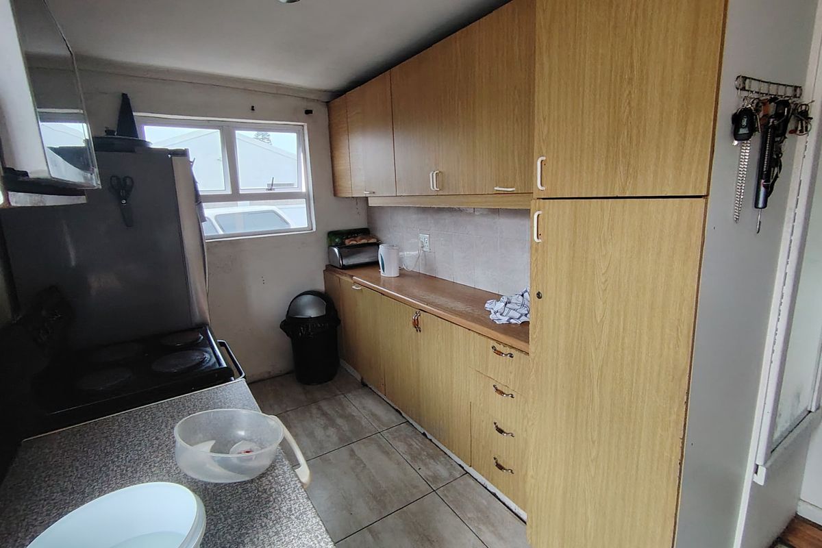 A functional kitchen featuring laminate cabinetry, tiled flooring, and built-in cooking appliances, offering a dated aesthetic ready for modernization.