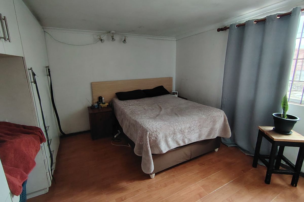 A bedroom featuring built-in cupboards and laminate flooring, requiring cosmetic updates to the walls and ceiling to improve its overall condition.