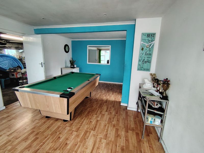 A multi-purpose living area featuring laminate flooring and recessed lighting, currently utilized as a recreational space.