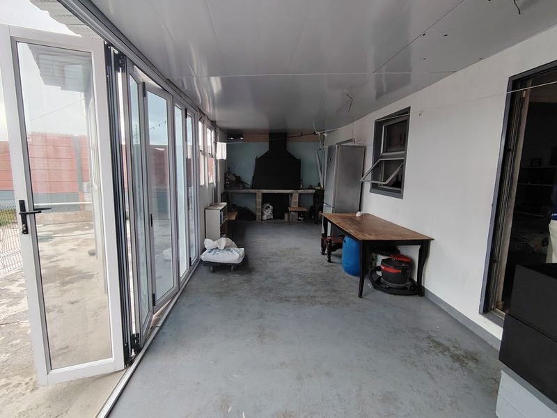Enclosed patio area featuring built-in braai, concrete flooring, and large bi-fold doors providing access to the outdoor space.