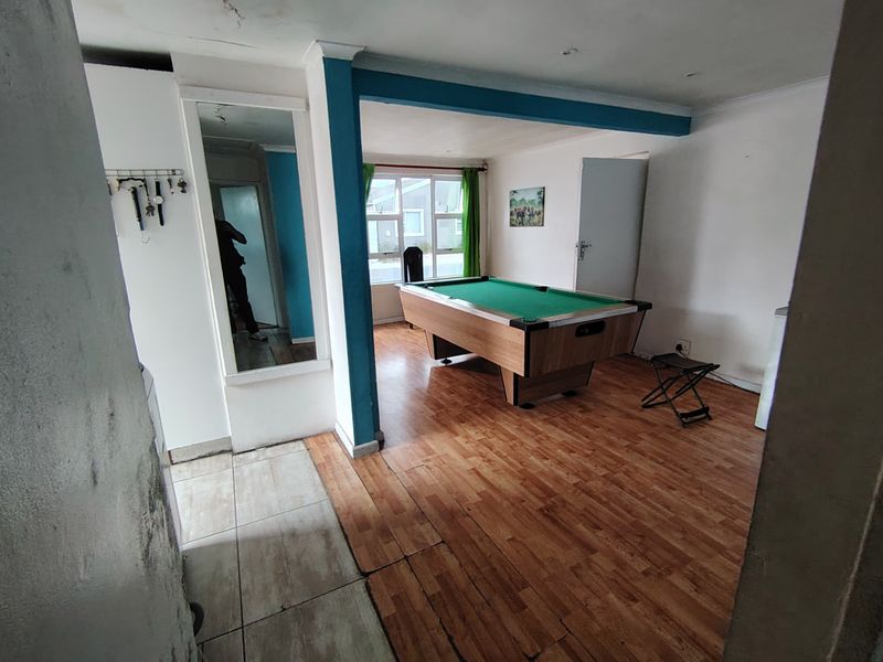 Living area featuring a mix of laminate and tiled flooring, with a built-in mirror and blue accent structural beam.