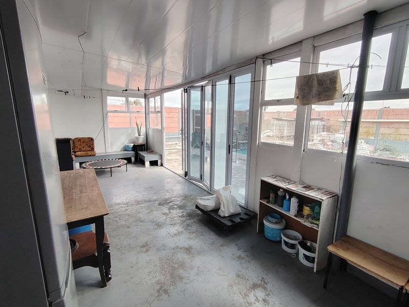 Enclosed patio area featuring bi-fold doors, concrete flooring, and large windows, offering a versatile space with direct access to the outdoor area.