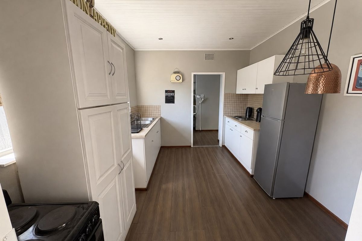 A functional kitchen featuring white cabinetry, tiled backsplash, wood-look flooring, and a tongue and groove ceiling, providing a clean and practical workspace.