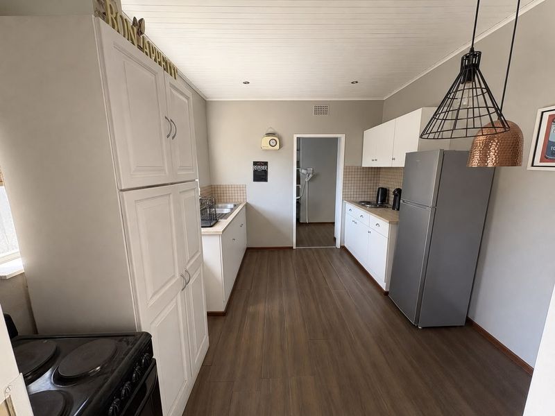 A functional kitchen featuring white cabinetry, tiled backsplash, wood-look flooring, and a tongue and groove ceiling, providing a clean and practical workspace.
