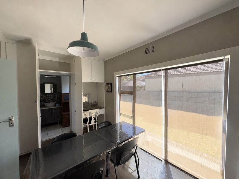 Dining area featuring laminate flooring, built-in cabinetry, and a large sliding glass door providing access to the exterior.