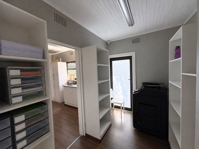A functional home office space featuring built-in shelving, laminate flooring, and direct access to the exterior.