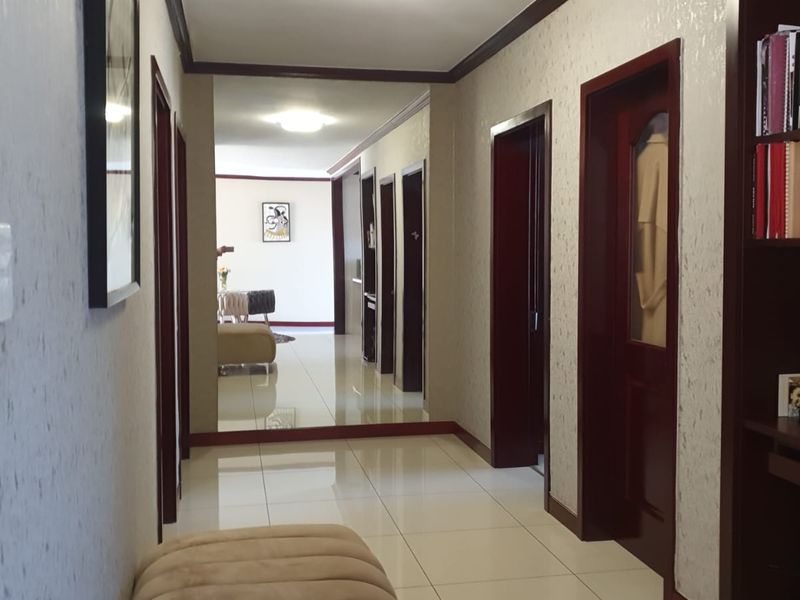 A well-lit hallway featuring tiled flooring, dark wood door frames, and a large wall-mounted mirror that enhances the sense of space.
