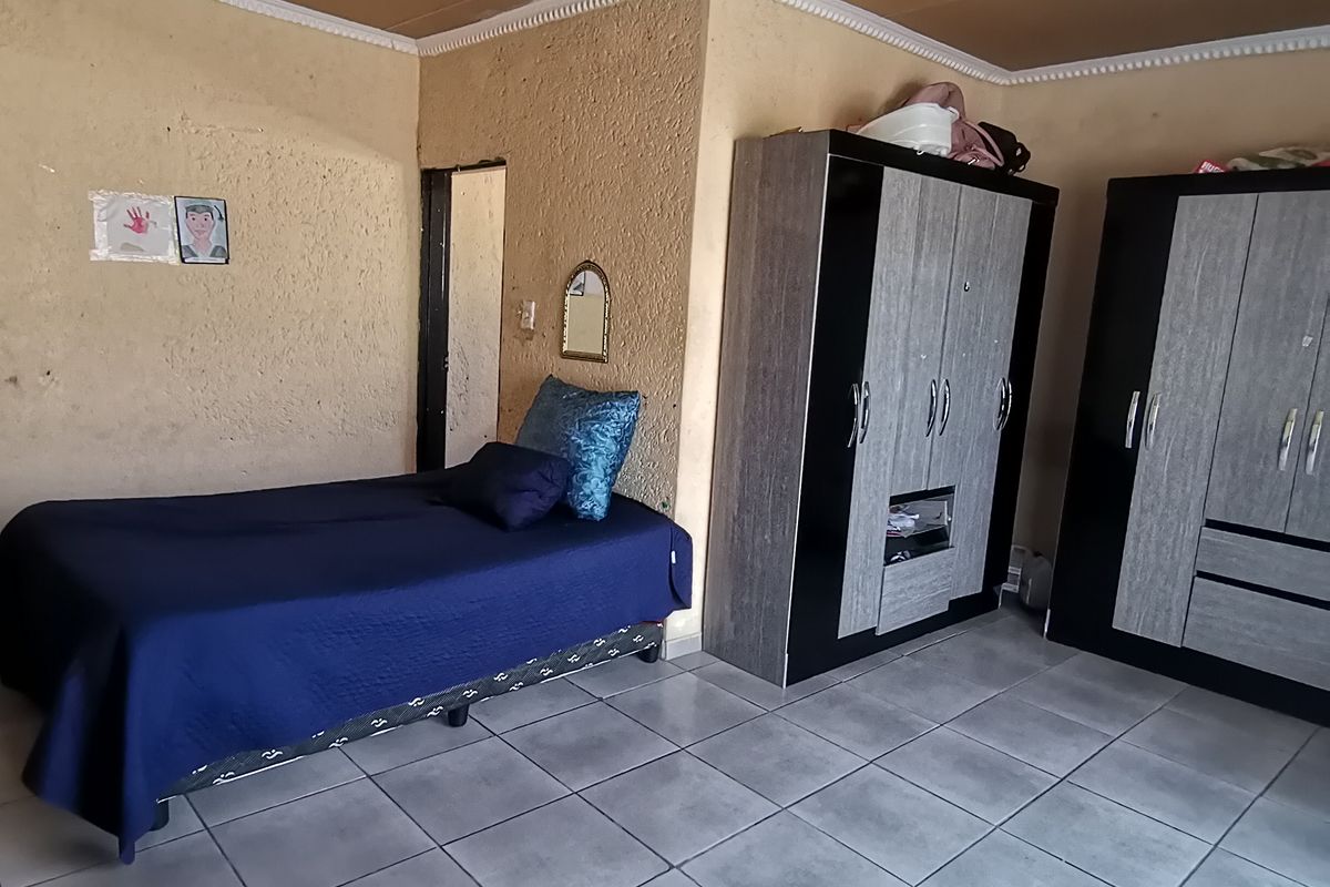 A bedroom featuring tiled flooring, textured walls, and ceiling panels. The space requires cosmetic updates to improve the overall finish and aesthetic appeal.