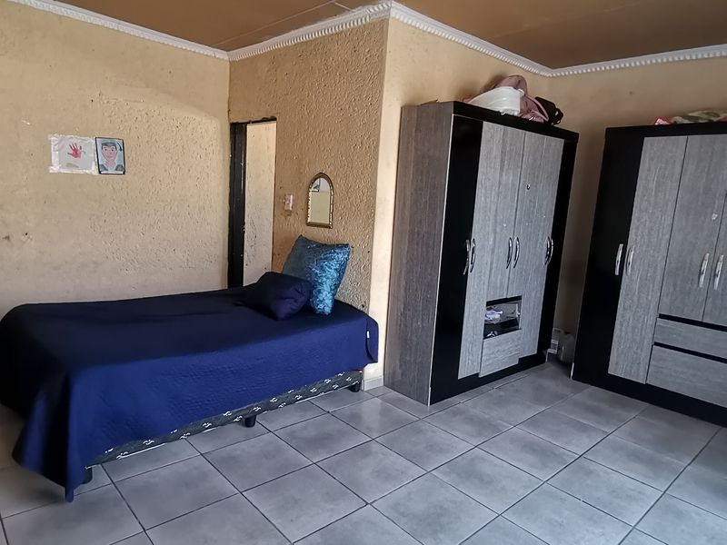 A bedroom featuring tiled flooring, textured walls, and ceiling panels. The space requires cosmetic updates to improve the overall finish and aesthetic appeal.