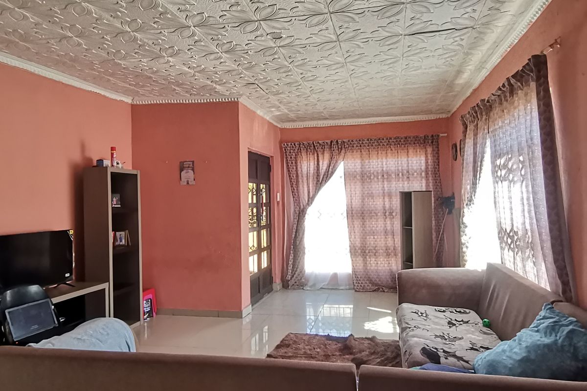 Spacious living room featuring decorative ceiling tiles, tiled flooring, and access to the exterior via a sliding glass door.