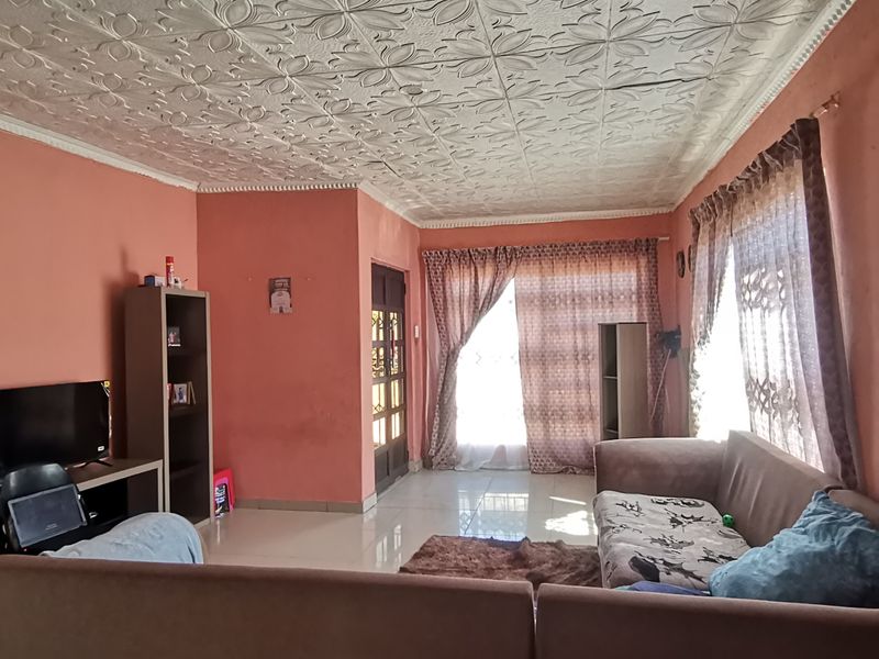 Spacious living room featuring decorative ceiling tiles, tiled flooring, and access to the exterior via a sliding glass door.