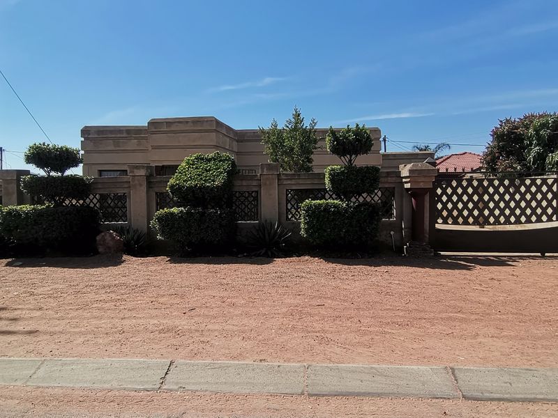Front view of the property featuring a solid boundary wall with decorative metal lattice inserts and a secure driveway gate.