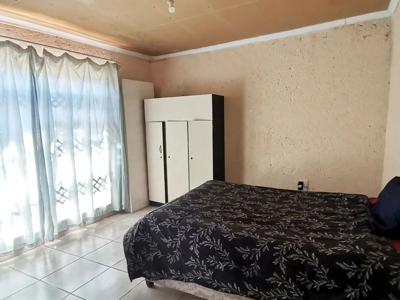 A bedroom featuring tiled flooring, textured walls, and ceiling panels, offering a functional space in need of cosmetic updates.