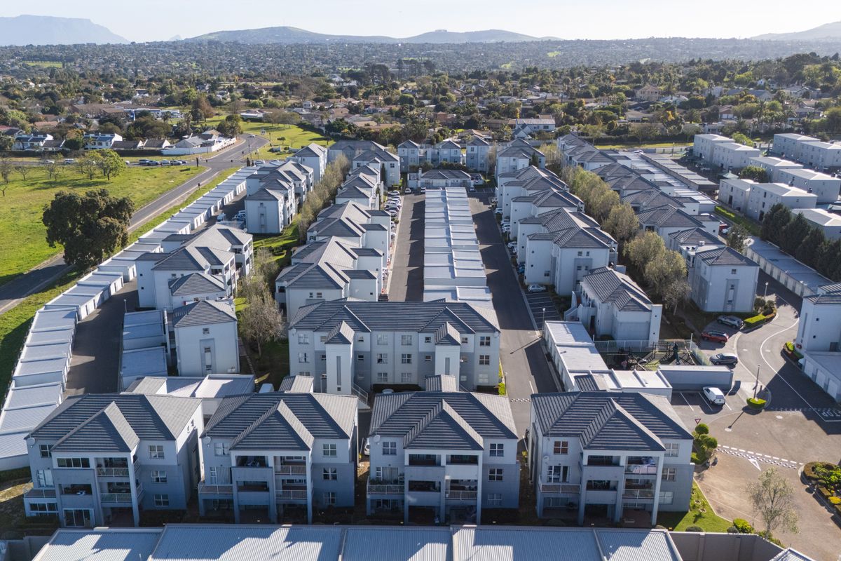 Aerial view of a modern residential apartment complex featuring multiple multi-story buildings, tiled roofs, and organized parking infrastructure.