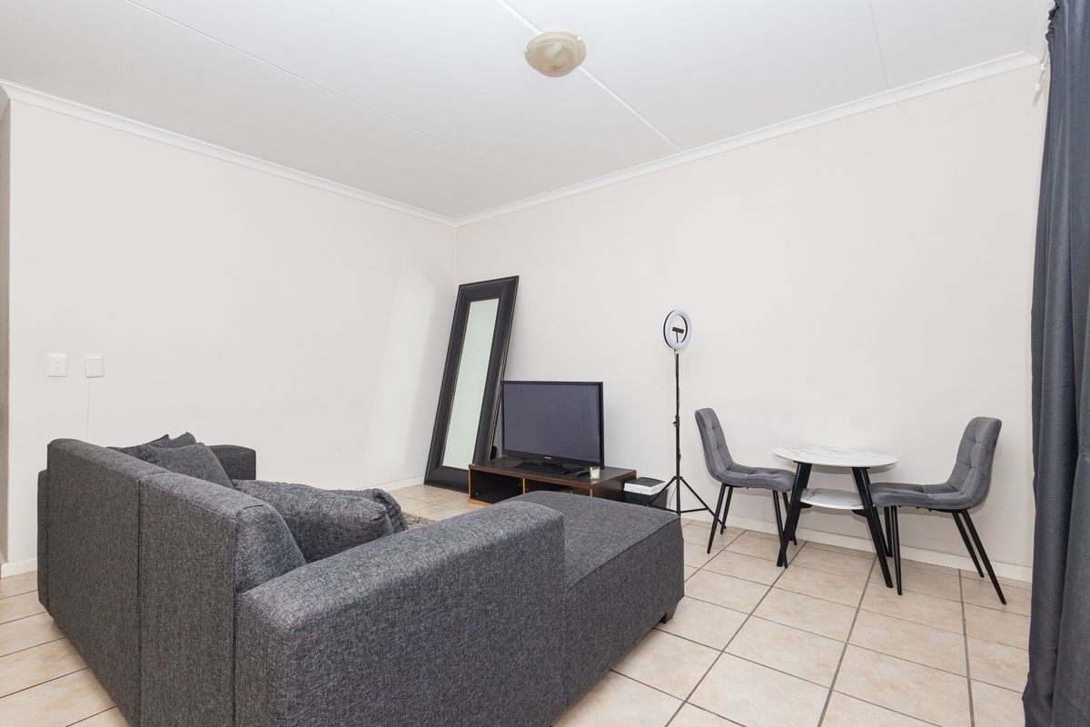 A functional living area featuring neutral tiled flooring and a coved ceiling, providing a versatile space for relaxation and dining.