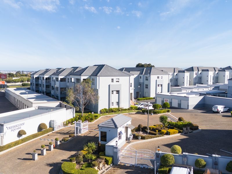 Aerial view of Vredekloof Square apartment complex, featuring a secure gated entrance, paved driveways, and well-maintained communal landscaped gardens.