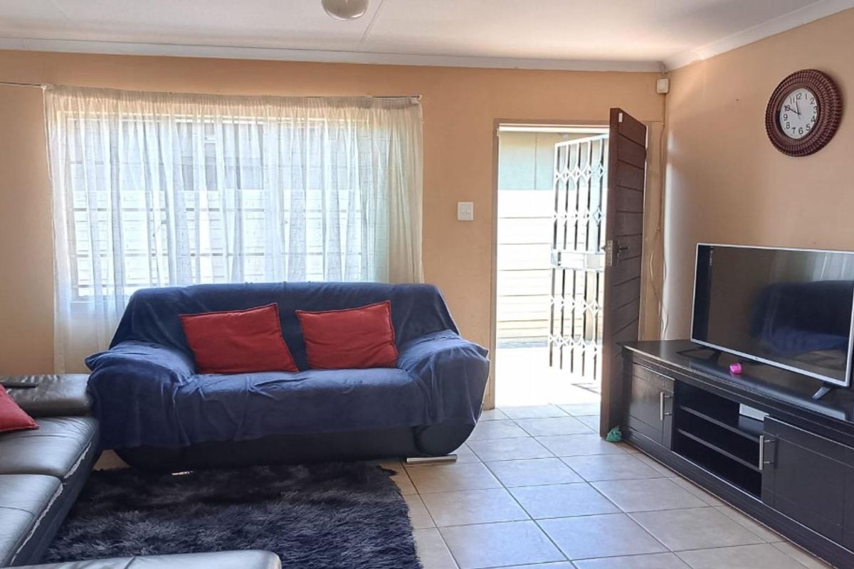 A living room featuring tiled flooring and direct access to the exterior via a security gate.