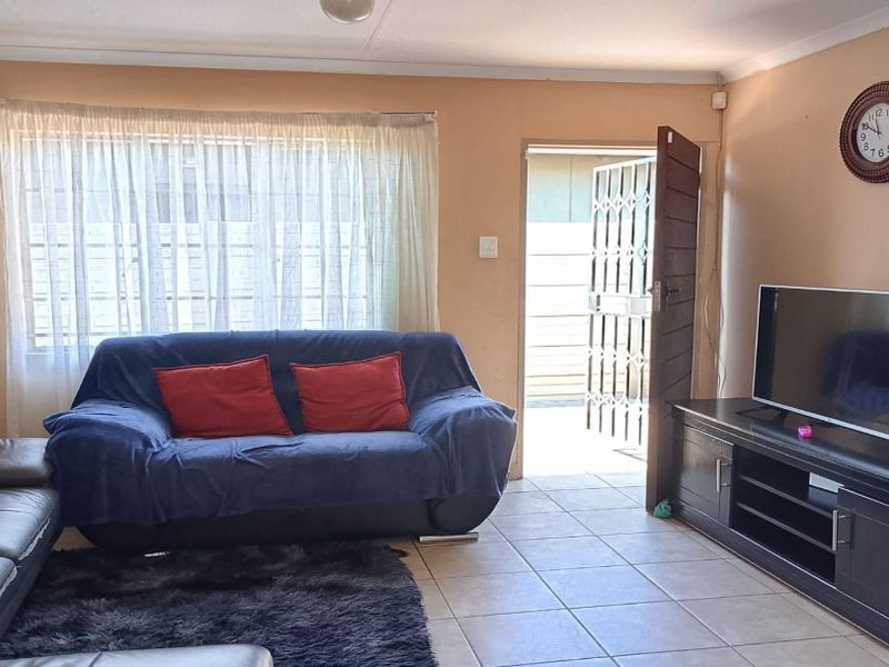 A living room featuring tiled flooring and direct access to the exterior via a security gate.