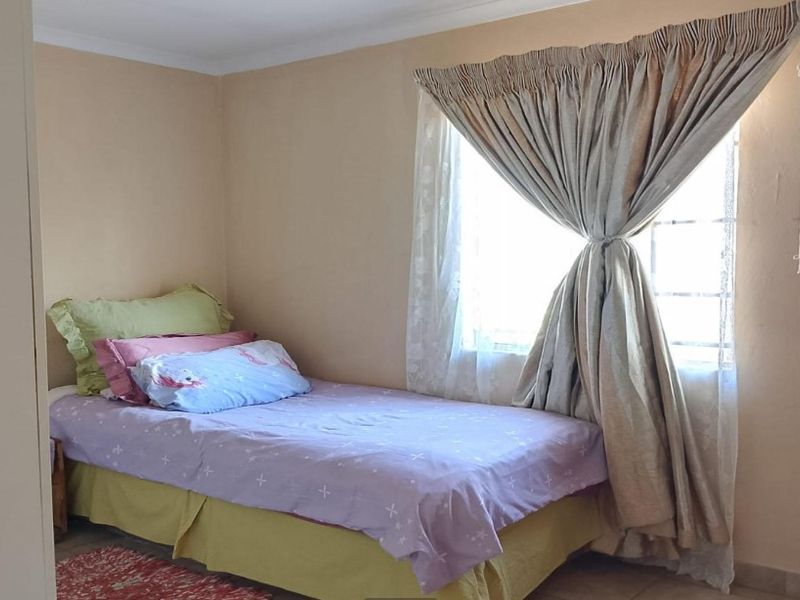 A simple bedroom featuring a window with curtains and neutral wall finishes.