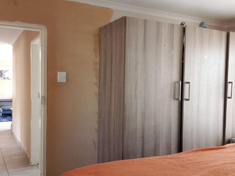 Bedroom featuring a built-in wardrobe and unfinished wall surfaces, with a view through to an adjacent living area.