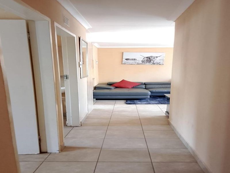 A tiled hallway providing access to adjacent rooms, leading towards a living area with neutral wall finishes.
