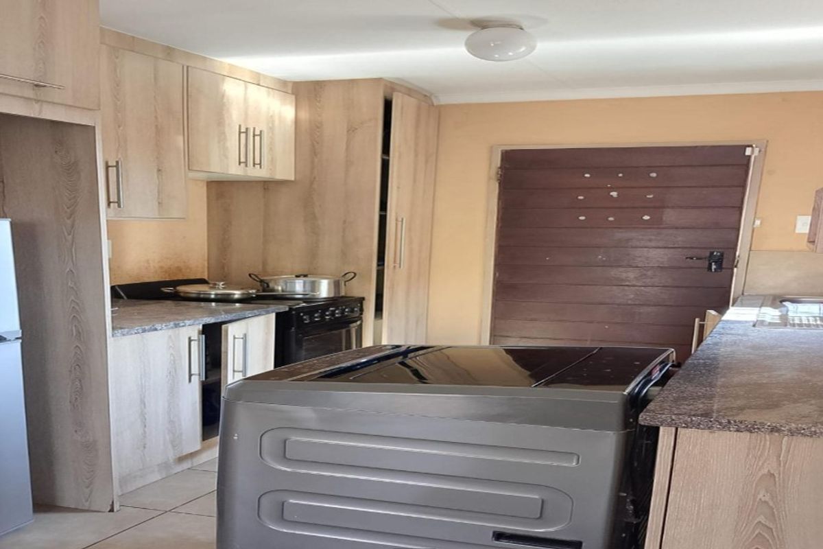 A functional kitchen featuring light wood-look cabinetry, laminate countertops, and tiled flooring, offering a practical layout for daily meal preparation.