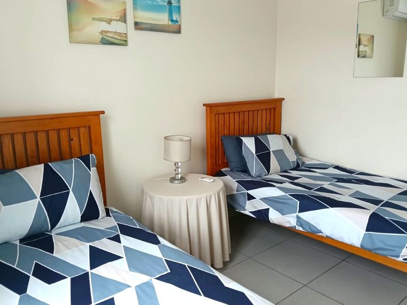 A functional bedroom featuring tiled flooring and an integrated air conditioning unit, currently configured with twin beds.