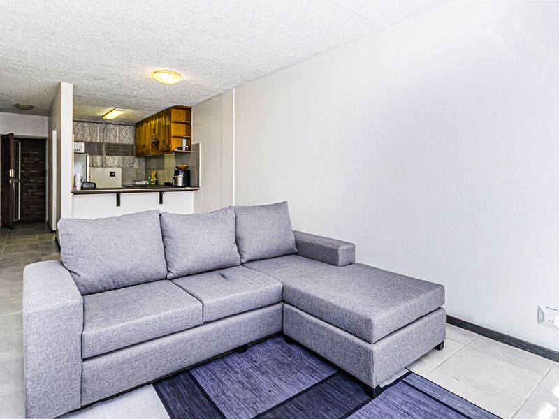 Open plan living area featuring tiled flooring and a functional kitchen with wooden cabinetry, providing a practical layout for daily living.