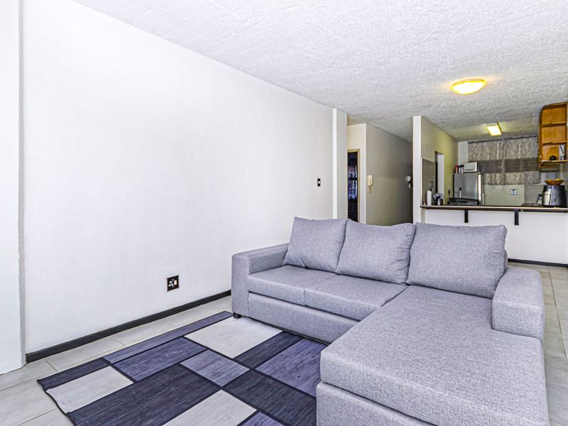 Open plan living area featuring tiled flooring and a functional kitchen with breakfast bar, providing a versatile space for daily living.